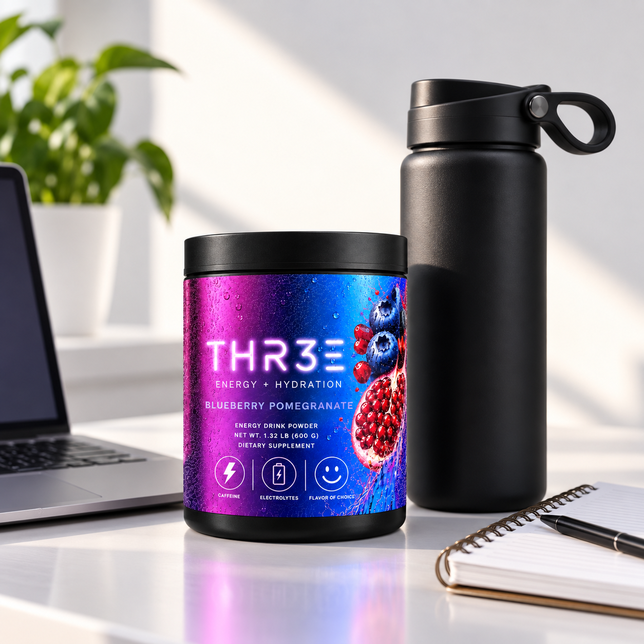 THR3E Blueberry Pomegranate tub on a desk with a laptop, water bottle, and notebook